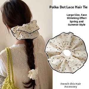 Detail view of large French lace hair scrunchie with black polka dots on cream fabric
