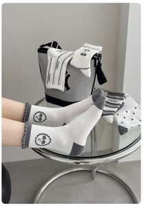 Détail de chaussettes en coton blanc avec talon gris, motif cerise et bordure ondulée