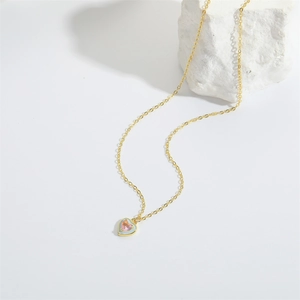 Detailed macro of gold heart pendant with pink gemstone and light blue enamel work