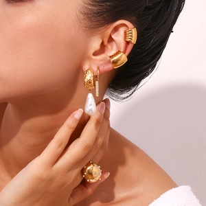 Detailed shot of vintage gold earrings with baroque pearl and ribbed cuff jewelry