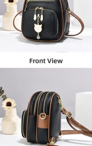 Detail view of mini black leather backpack with brown trim and golden cat charm pendant