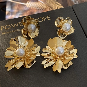 Gros plan de boucles d'oreilles fleur dorées avec perles blanches sur un coffret noir