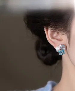 Detailed side view of silver needle square pearl and blue zircon cluster earrings