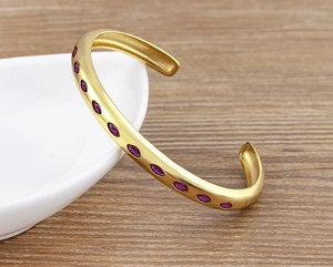 Detail showing 18k gold plated cuff bracelet with purple marquise cut zirconia stones