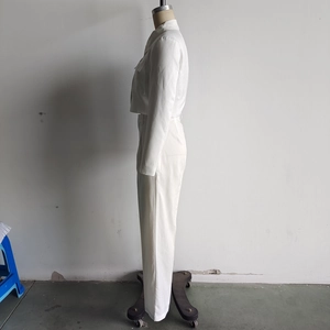 Detail of white two-piece set featuring a cropped button-up jacket and straight-leg trousers