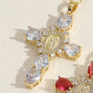 Detailed macro view of gold cross pendant with clear cubic zirconia and center relief
