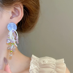 Detailed close-up of handmade beaded fringe earrings with purple marble resin and white pearls