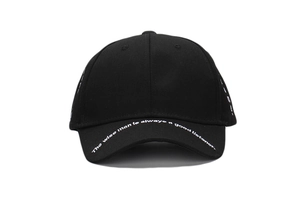 Detail of black cotton baseball cap brim featuring white printed motivational text quote