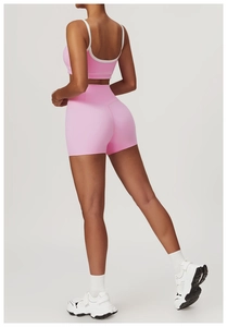 Pink yoga set featuring high-waisted shorts and sports bra with white piping detail