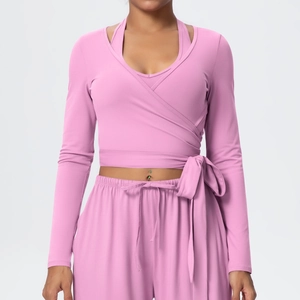 Front view of pink long sleeve wrap yoga top with side ties and matching joggers