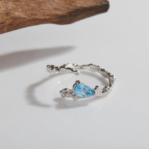 Macro detail of S925 sterling silver stamp and light blue drop-shaped gemstone on textured ring