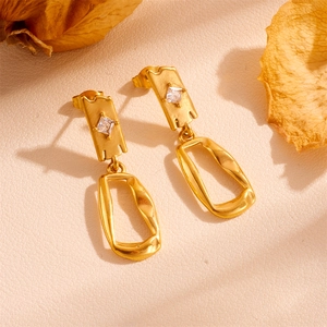Detailed shot of retro gold devil's eye earrings with square zirconia on beige leather