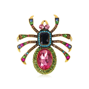 Close-up of spider brooch with colorful crystals and pink gemstone on golden base