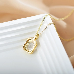Macro detail of a gold necklace featuring a rectangular clear gem pendant and O-chain