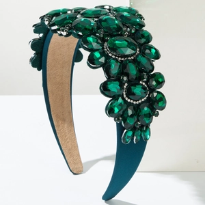 Macro detail of emerald-green gemstones on a blue satin headband for formal events