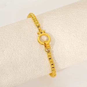 Gold stainless steel beaded bracelet with large OT toggle clasp on textured stand