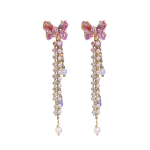 Elegant butterfly earrings with pink crystals and long pearl tassels on white background