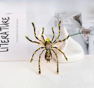 Macro shot of spider brooch featuring green zircons and yellow-green leg details