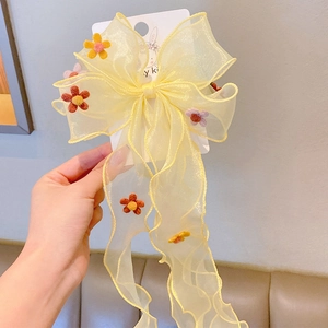 Detail of yellow tulle bow hair clip with colorful floral accents for girls
