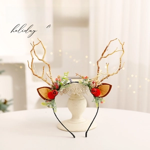 Handmade Christmas deer antler headband with red berries on an elegant vintage stand
