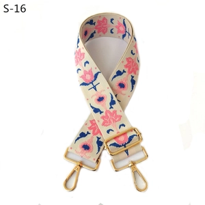 Detail of adjustable beige bag strap with pink and blue floral embroidery and gold hooks