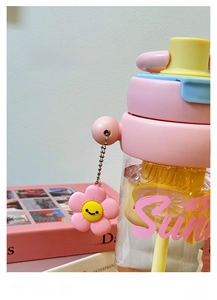Detail van roze en gele beker met rietje, citroenschijfjes en een bloemenhanger