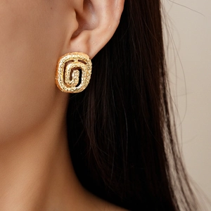 Detailed view of golden irregular spiral earrings featuring a textured hammered metal finish