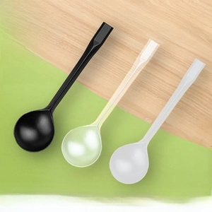 Close-up of thick disposable plastic spoons in black, yellow, and white with long handles