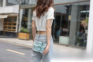 Rear view of a model wearing a clear PVC crossbody bag with a light blue inner pouch