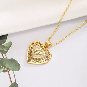Detail of gold hollow heart pendant necklace with micro-set zircon on white silk background