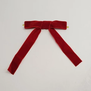 Detail of red velvet Christmas bow with gold metal clip on white background