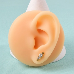 Close-up of golden 16G internally threaded labret stud with white crystals on ear model