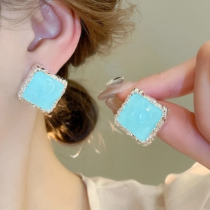 Détail de boucles d'oreilles carrées marbre bleu clair avec bord argenté sur modèle
