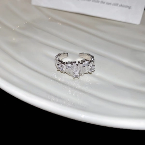Detailed view of irregular textured silver ring with zircons on white ceramic plate