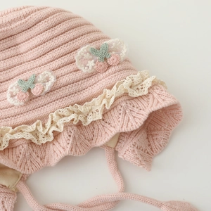 Pink knit baby winter hat with lace trim, cherry accents and chin strap for warmth