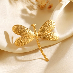 Minimalist golden dragonfly ring with hammered texture on elegant silk fabric background