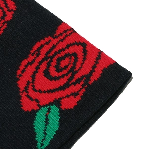 Close-up of knit beanie showing detailed red rose jacquard pattern on black fabric