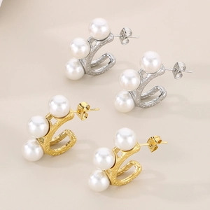 Detailed view of gold and silver C-shaped pearl earrings with a hammered metal texture
