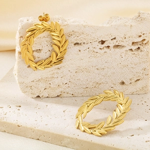 Detail view of 18k gold plated laurel leaf hoop earrings on beige travertine stone
