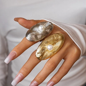 Close-up of gold and silver textured oval rings with pearl inlay on model hand