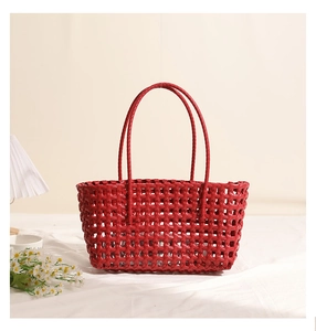 Detail of red hollow woven shoulder bag with intricate plastic weave texture for beach vacations