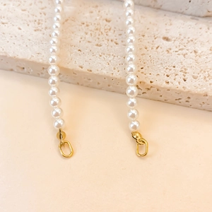 Detail view of glossy white pearls with golden clasp on natural stone background