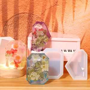 Detail showing various geometric resin molds with embedded dried flowers and crystal shapes