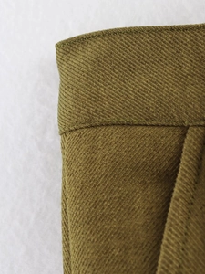 Macro detail of olive green twill jacket fabric with precision stitching and texture