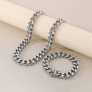 Detail of silver 13mm Cuban link chain set with a unique dragon clasp on a beige background
