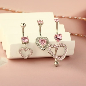 Three-piece silver heart belly button rings set with pink cubic zirconia on display stand