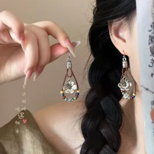 Ethnic drop earrings with silver flower pendant and colorful beads worn by a model