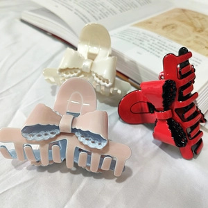 Three elegant acetate shark hair clips with lace bow designs in pink, cream and red