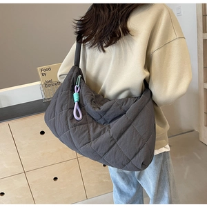 Detail of dark grey quilted tote bag with purple and blue knot charm on a model