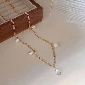 Detailed view of 925 silver gold chain with five baroque pearls on warm beige background